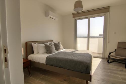 a bedroom with a bed and a window and a chair at Phaedrus Living Coral Suites Bliss in Larnaka