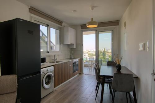 a kitchen with a black refrigerator and a table with chairs at Phaedrus Living Coral Suites Bliss in Larnaka