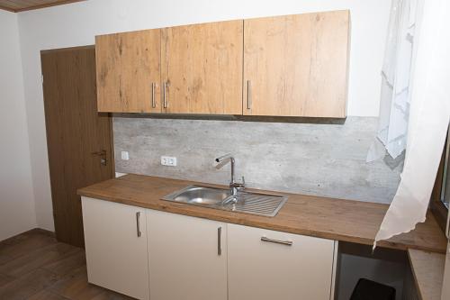 a kitchen with a sink and wooden cabinets at Gästehaus Lorz in Höchstadt an der Aisch