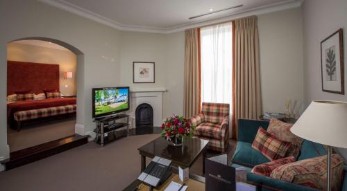 a living room with a couch and a television and a bed at Bedford Lodge Hotel & Spa in Newmarket