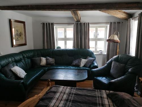 a living room with a green couch and two chairs at Pension Am Buhnenkopf in Tangermünde