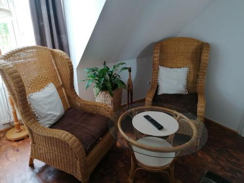 two wicker chairs and a table in a room at Pension Am Buhnenkopf in Tangermünde