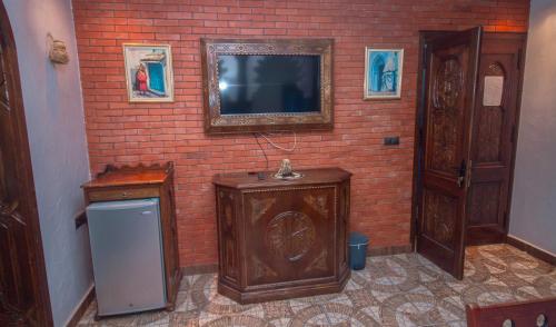 Habitación con pared de ladrillo y TV. en Casa NORTE, en Chefchaouen