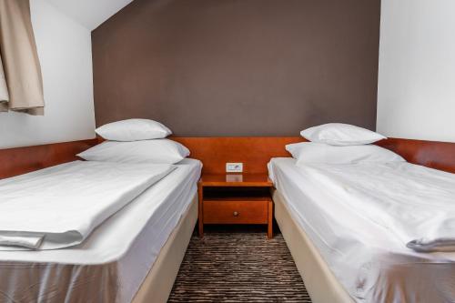 two beds in a room with a table between them at Hotel Kranjska Gora in Kranjska Gora