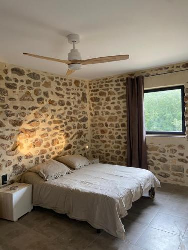 een slaapkamer met een bed met een stenen muur bij Mas Bô Regard in Aiguèze