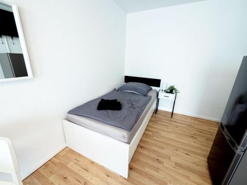 a small white bedroom with a bed and a television at Work & stay in Ahrensburg in Ahrensburg