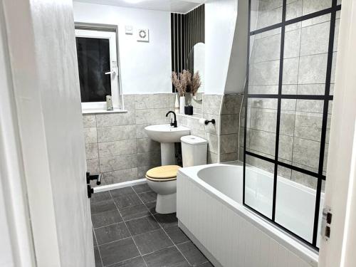 a bathroom with a toilet and a tub and a sink at Luxury 3 Bed Home In London in London