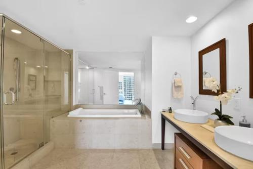 uma casa de banho com 2 lavatórios, um chuveiro e uma banheira. em Amazing 2 Bedroom at Icon in the Heart of Brickell em Miami