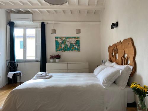Schlafzimmer mit einem großen weißen Bett mit einem Kopfteil aus Holz in der Unterkunft La Casa della Torre in Pisa