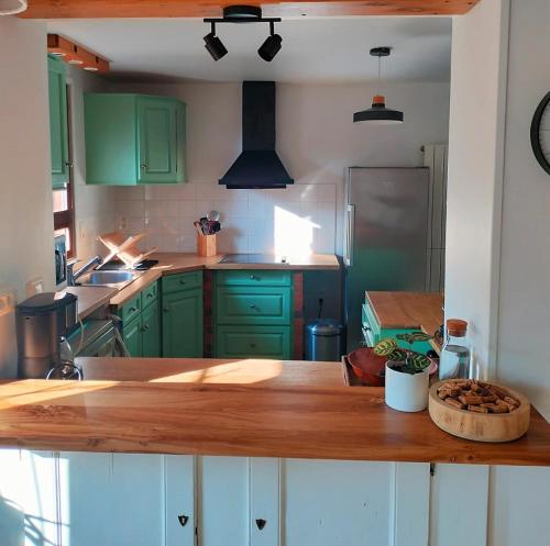 uma cozinha com armários verdes e um balcão de madeira em Gîte Au gré du vent - 12 personnes - Calme, nature et confort em La Goutelle