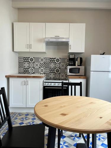 une cuisine avec des armoires blanches et une table en bois dans l'établissement Le Grand Mondi, à Mareuil-sur-Cher