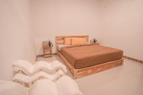 een slaapkamer met een bed en 2 witte stoelen bij Villa Dangka in Kubupenlokan