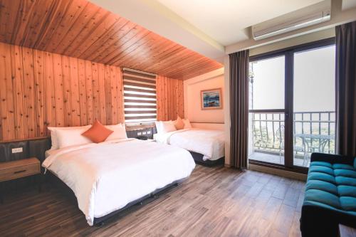 een slaapkamer met 2 bedden en een groot raam bij Chill hill cottage in Taiping
