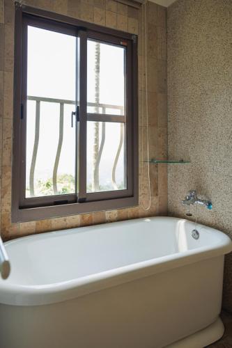 a bath tub in a bathroom with a window at Chill hill cottage in Taiping