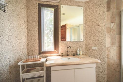 ein Bad mit einem Waschbecken und einem Spiegel in der Unterkunft Chill hill cottage in Taiping