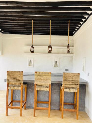 a table with three chairs in a room at Milimani Villa-Fully airconditioned Villa in Shela