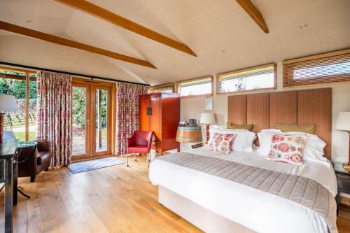 a bedroom with a bed and a desk and windows at Three Choirs Vineyards in Newent