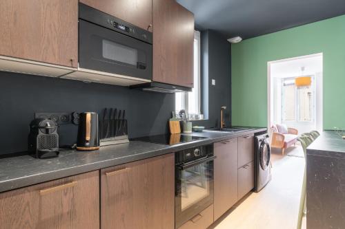 une cuisine avec des armoires en bois et un four à plaques de cuisson dans l'établissement Appartement élégant proche Tramway & Centre-Ville, à Nantes