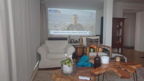 ein Wohnzimmer mit einem Sofa, einem Stuhl und einem Tisch in der Unterkunft שרון על המים in Herzliya B
