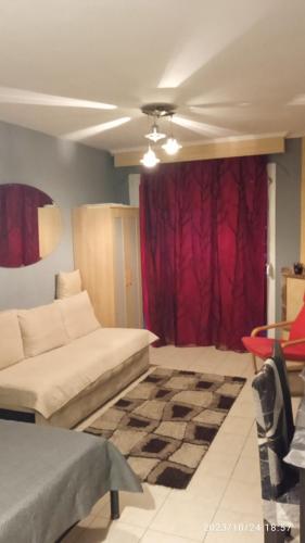 a living room with a couch and a red curtain at Roses Apartments in Néa Michanióna