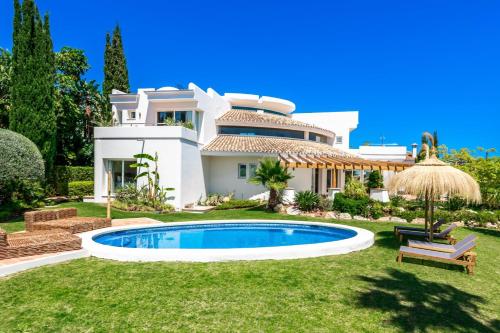 a villa with a swimming pool in front of a house at All About La Redonda Villa in Estepona