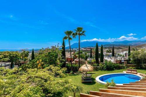 a garden with a swimming pool and palm trees at All About La Redonda Villa in Estepona