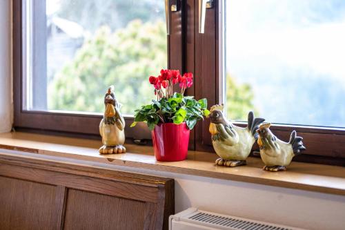 a window sill with a vase with flowers and rubber ducks at Ferienwohnung Gatscherhof in Luson