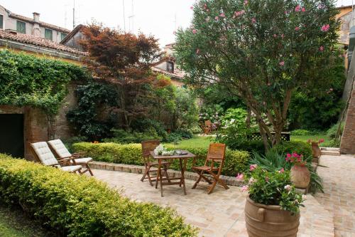 een patio met een tafel en stoelen en een tuin bij San Giacomo in Venetië