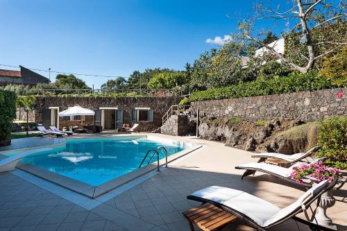 a swimming pool with chairs and a stone wall at Montefiore in Ragalna