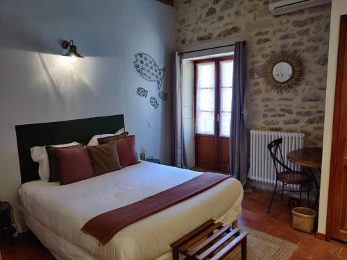 a bedroom with a bed and a table and a window at L'Instant Sévigné in Grignan