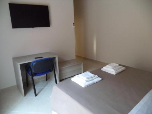 a room with a blue chair and a desk with a television at B&B SALento in San Cesario di Lecce