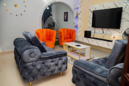 Budget Bliss Suites في بنين سيتي: غرفة معيشة مع كرسيين وتلفزيون بشاشة مسطحة
