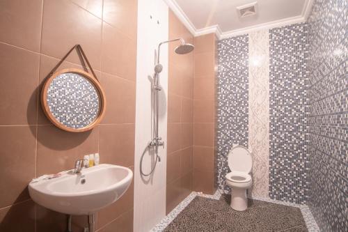 een badkamer met een wastafel, een toilet en een spiegel bij Villa Dangka in Kubupenlokan