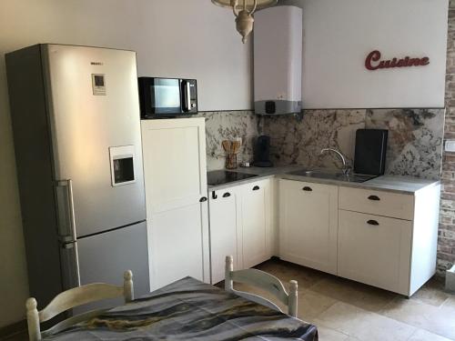 uma cozinha com armários brancos, um frigorífico e uma mesa em Partie de mas en campagne em Cavaillon