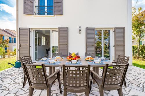 une table avec des chaises et un bol de fruits dessus dans l'établissement Gîte La Villa Omagny Paris Marne-la-Vallée, à Magny-le-Hongre