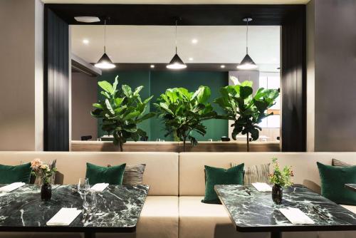 two tables in a restaurant with green plants at Tapestry by Hilton Ambasciatori Hotel in Mestre