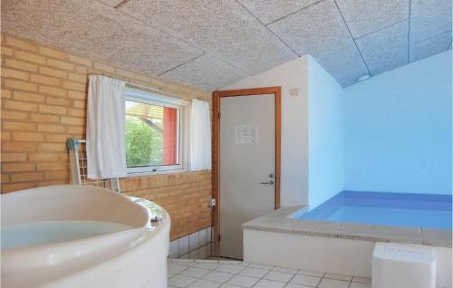 HejlsにあるNice Home In Hejls With 3 Bedrooms, Wifi And Indoor Swimming Poolの大きなバスルーム(バスタブ、窓付)