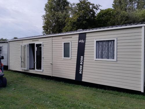 a large white mobile home with a window at La Palmyre - Les Mathes - Mobil home 3 ch LUXUEUX de 40m2 - Grand emplacement dans village loisirs 4 étoiles - "les Charmettes 394" proche FUN ZONE in Les Mathes