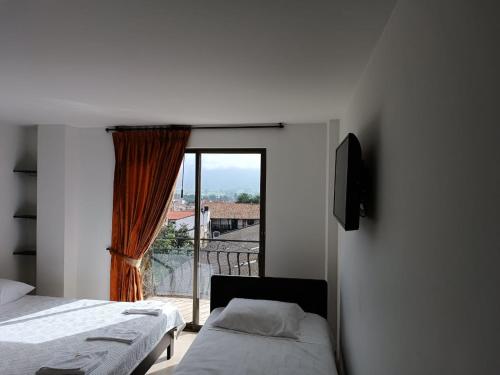 a bedroom with two beds and a large window at SANTA HELENA HOSPEDERIA in Tibasosa