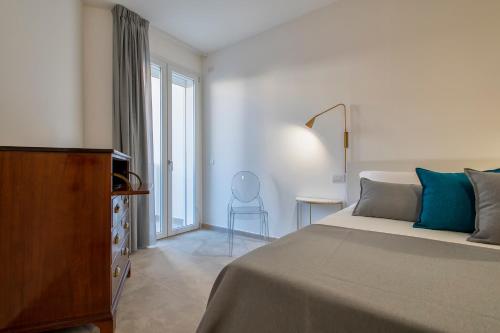 a bedroom with a bed and a dresser and a window at RelaisApartments Centro in Alghero