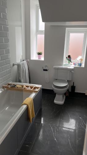 a bathroom with a tub and a toilet and a sink at Goncalves place in Bournemouth