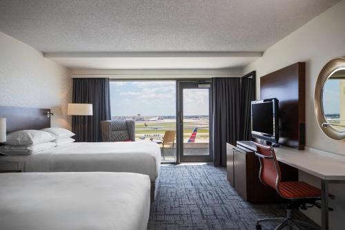 アトランタにあるルネッサンス コンコース アトランタ エアポート ホテルのベッド2台、デスク、テレビが備わるホテルルームです。