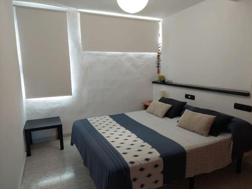 a bedroom with a bed and two windows at Apartamento, piscina y playa in Grao de Castellón