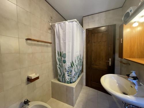 y baño con lavabo, aseo y cortina de ducha. en 050 Trilocale in centro, Pinzolo, en Pinzolo