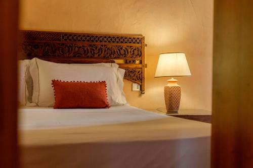 ヴィッラシミーウスにあるLuna Bay Home Retreat con vista sulla baia di Porto Luna a 2 km da Villasimiusのベッドルーム1室(赤い枕とランプ付きのベッド1台付)