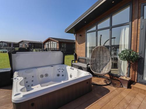 a hot tub sitting on a deck next to a house at 1 Delamere Point in Northwich