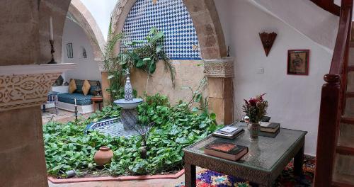 a living room with a garden with a table and a room with a table at Dar Rahaothello in Essaouira