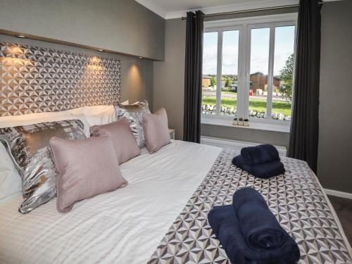 um quarto com uma cama grande e uma janela grande em 28 Delamere Point em Northwich