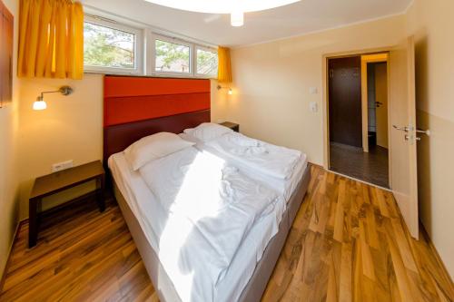 Schlafzimmer mit einem großen weißen Bett und Holzboden in der Unterkunft Kölpinsee 03 in Eldenburg