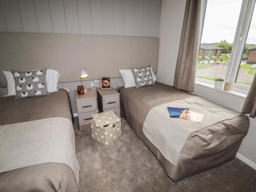 a bedroom with two beds and a window at 44 Delamere Point in Northwich